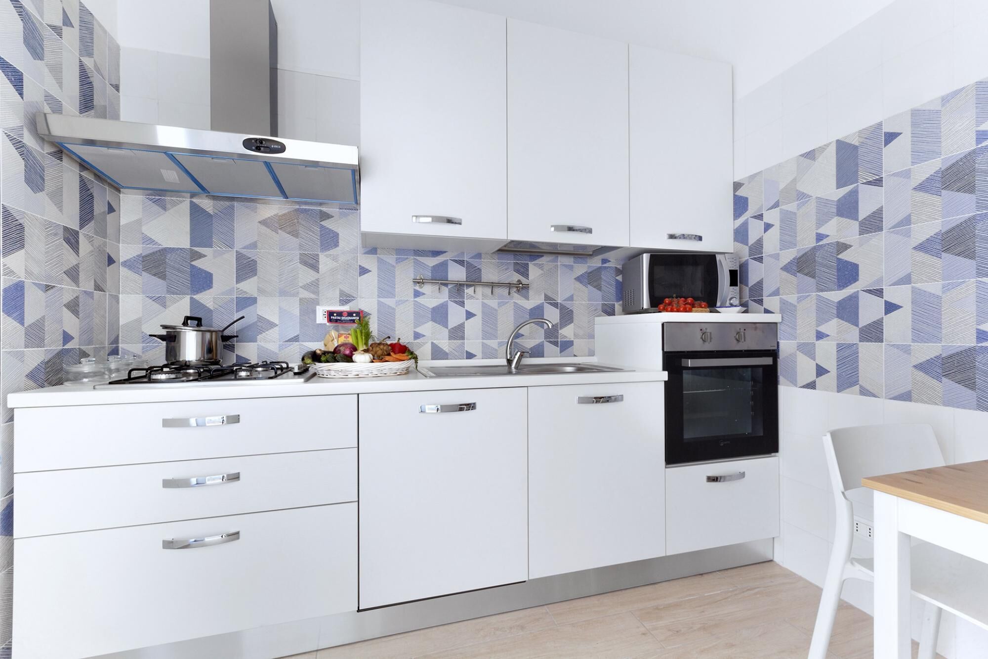 A modern kitchen with white cabinets, a gas stove, a microwave, and a sink.