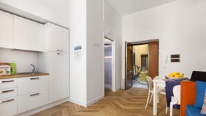 A modern kitchen with white cabinets and a wooden countertop, a dining area with a table and chairs, and a herringbone-patterned wooden floor. - Casa 80 in Sorrento With 3 Bedrooms and 2 Bathrooms (Sorrento)