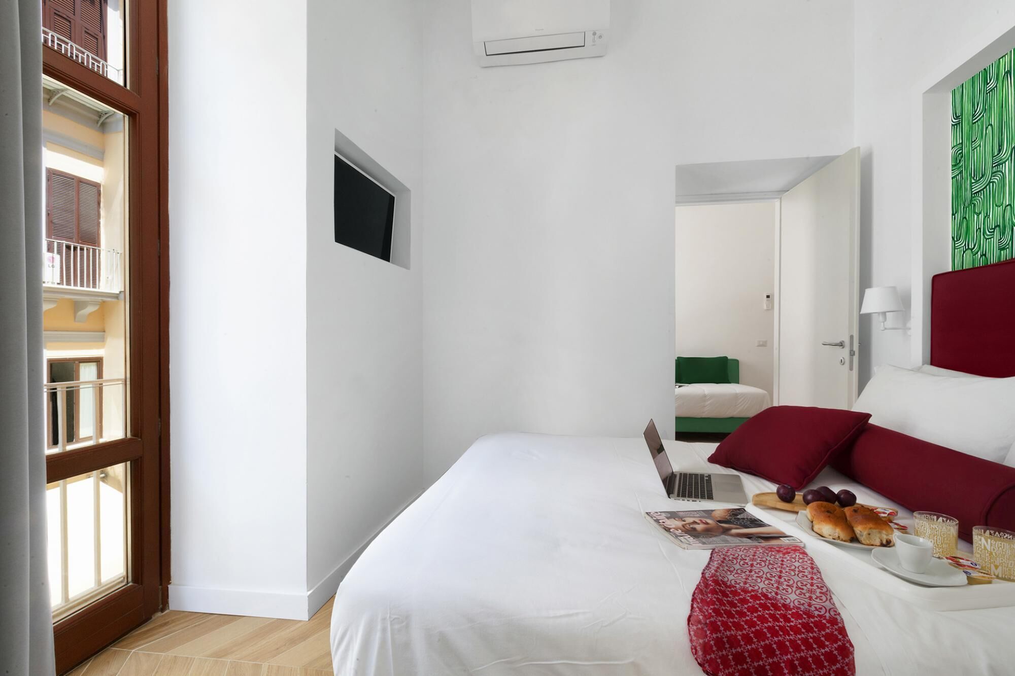 Een hotelkamer met een bed, een laptop, een tijdschrift en een ontbijttray.
