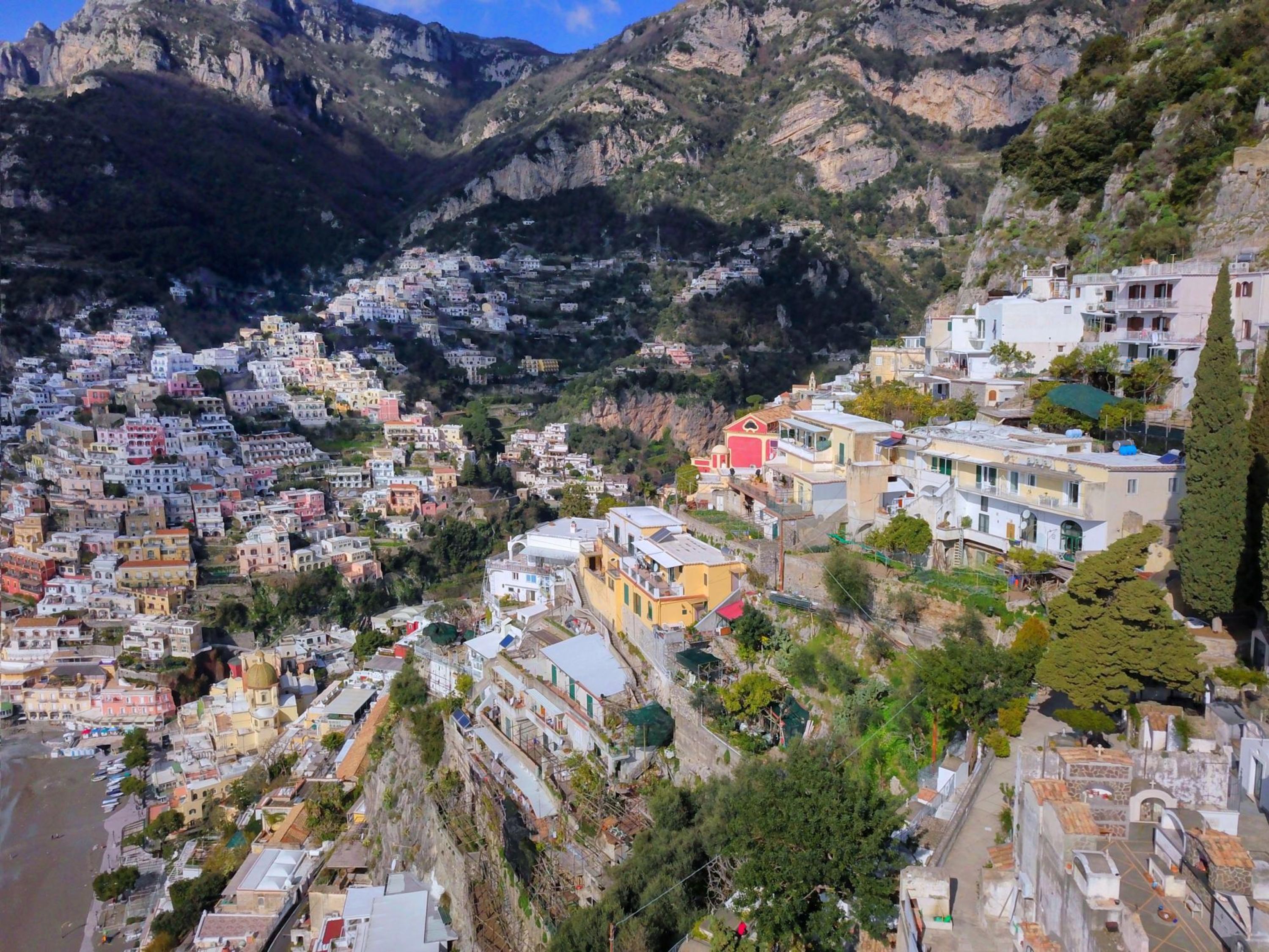 Une ville côtière où les bâtiments sont très rapprochés les uns des autres, avec des rues étroites et un paysage montagneux en arrière-plan.