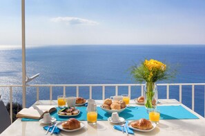 A breakfast table with croissants, orange juice, and a vase of flowers, overlooking the sea. - Villa Anna in Positano (Positano)