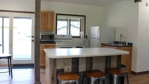 A kitchen with a central island, wooden cabinets, a microwave, and a refrigerator.