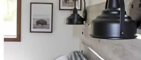 A bedroom with a bed, a kettle, and framed pictures on the wall.