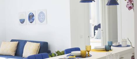 Una sala de estar moderna con sofá, mesa de comedor y lámparas colgantes.