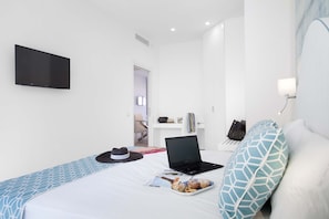 Une chambre d’hôtel équipée d’un lit, d’un ordinateur portable, d’une télévision et d’une table de chevet avec une lampe.