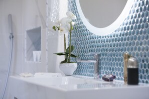 A bathroom with a white sink, a potted orchid, a mirror, and a blue tiled wall. - Sara Home 2 in Sorrento (Sorrento)