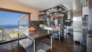A modern kitchen with stainless steel appliances, a large island, and a view of the sea. - Villa Elia in Massa Lubrense (Massa Lubrense)