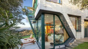 A modern house with a glass entrance, outdoor seating, and a view of the landscape. - Villa Elia in Massa Lubrense (Massa Lubrense)