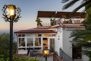 Ein modernes Haus mit einem Balkon, großen Fenstern und Meerblick.