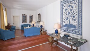 A room with a blue sofa set, a table with a lamp, and a large blue and white patterned tapestry on the wall. - Villa Stella in Massa Lubrense (Massa Lubrense)