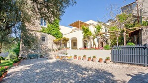 A cobblestone courtyard with a stone building, outdoor seating, and potted plants. - Villa Stella in Massa Lubrense (Massa Lubrense)