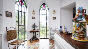 A room with two large stained glass windows, a wooden chair, a small table, and decorative bird figurines. - Villa Angelo in Sant Agnello (Sant'Agnello)
