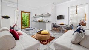 A modern living room with a sofa, ottoman, and dining area. - Appartamento Sorrento Suite de Charme 1 (Sorrento)