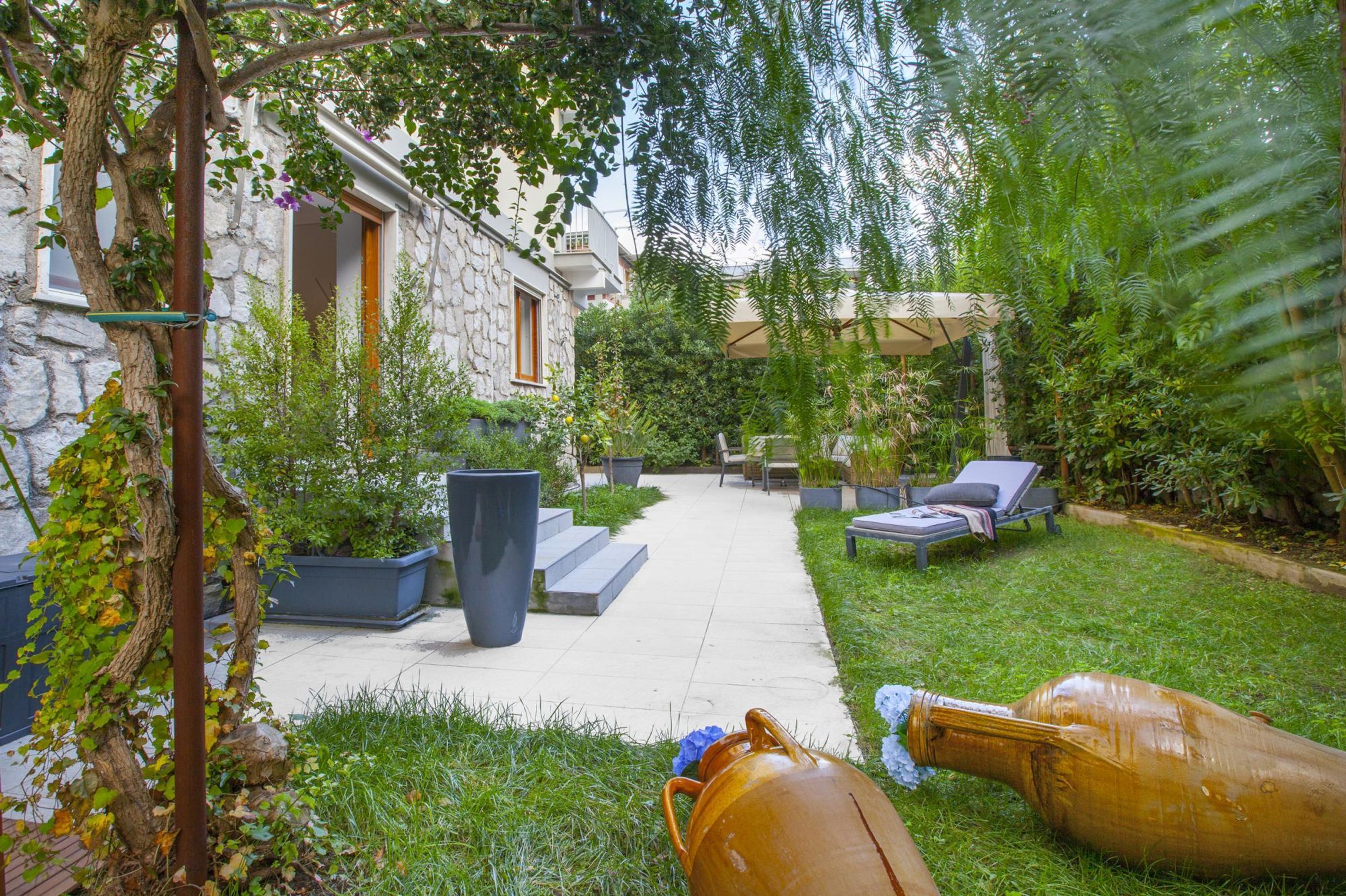 Ein Steingebäude mit Gartenpatiо, Sitzgelegenheiten im Freien und einem Weg.