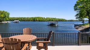 Um deck com mesa e cadeiras de frente para um lago, um cais e um barco.