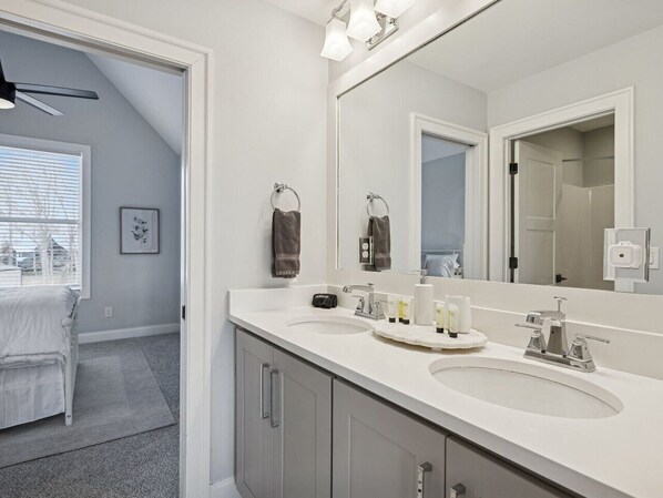 A modern bathroom with two sinks, a large mirror, and a ceiling fan.