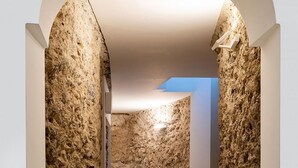 A narrow hallway with textured stone walls and a tiled floor.