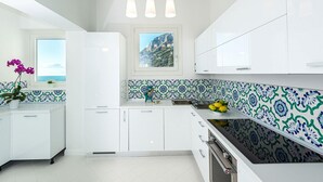 A modern kitchen with white cabinets, a black countertop, and blue and white patterned backsplash.