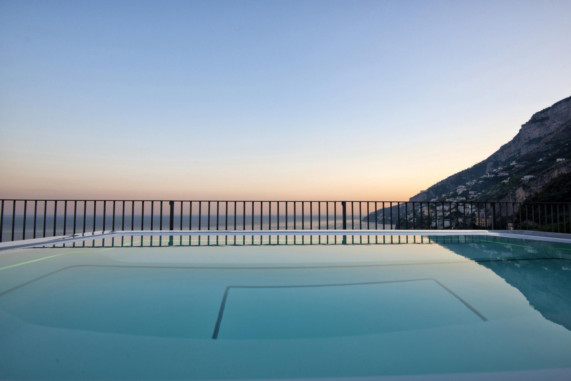 Klar udsigt over en swimmingpool med gelænder, omgivet af et bjergrigt landskab.