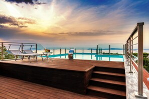 Une terrasse en bois avec des chaises longues et une piscine, offrant une vue panoramique.