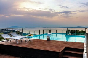 Un espace piscine avec des chaises longues et une vue sur la mer.