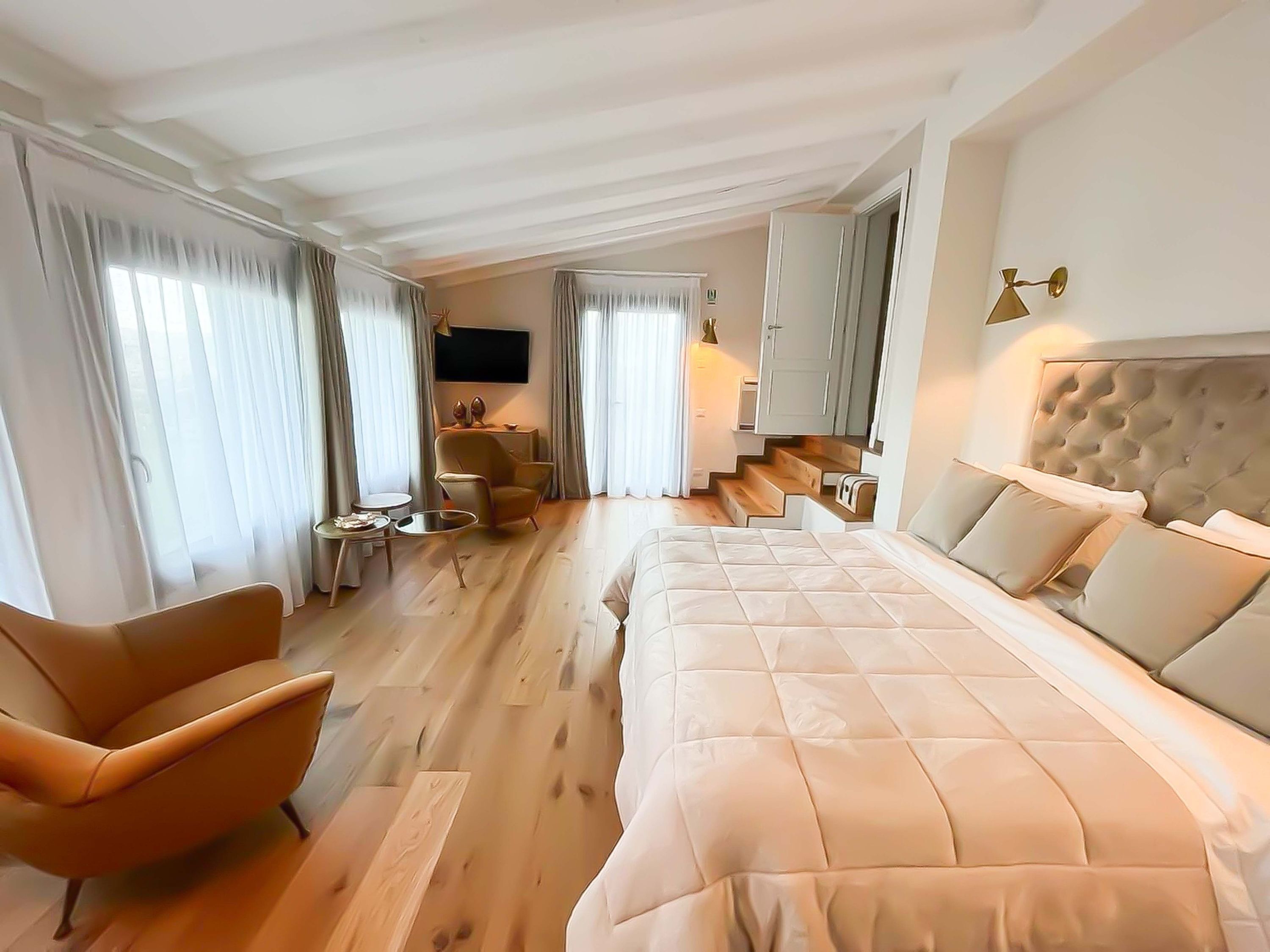 Une chambre d’hôtel moderne avec un grand lit, un canapé, une petite table et un téléviseur.