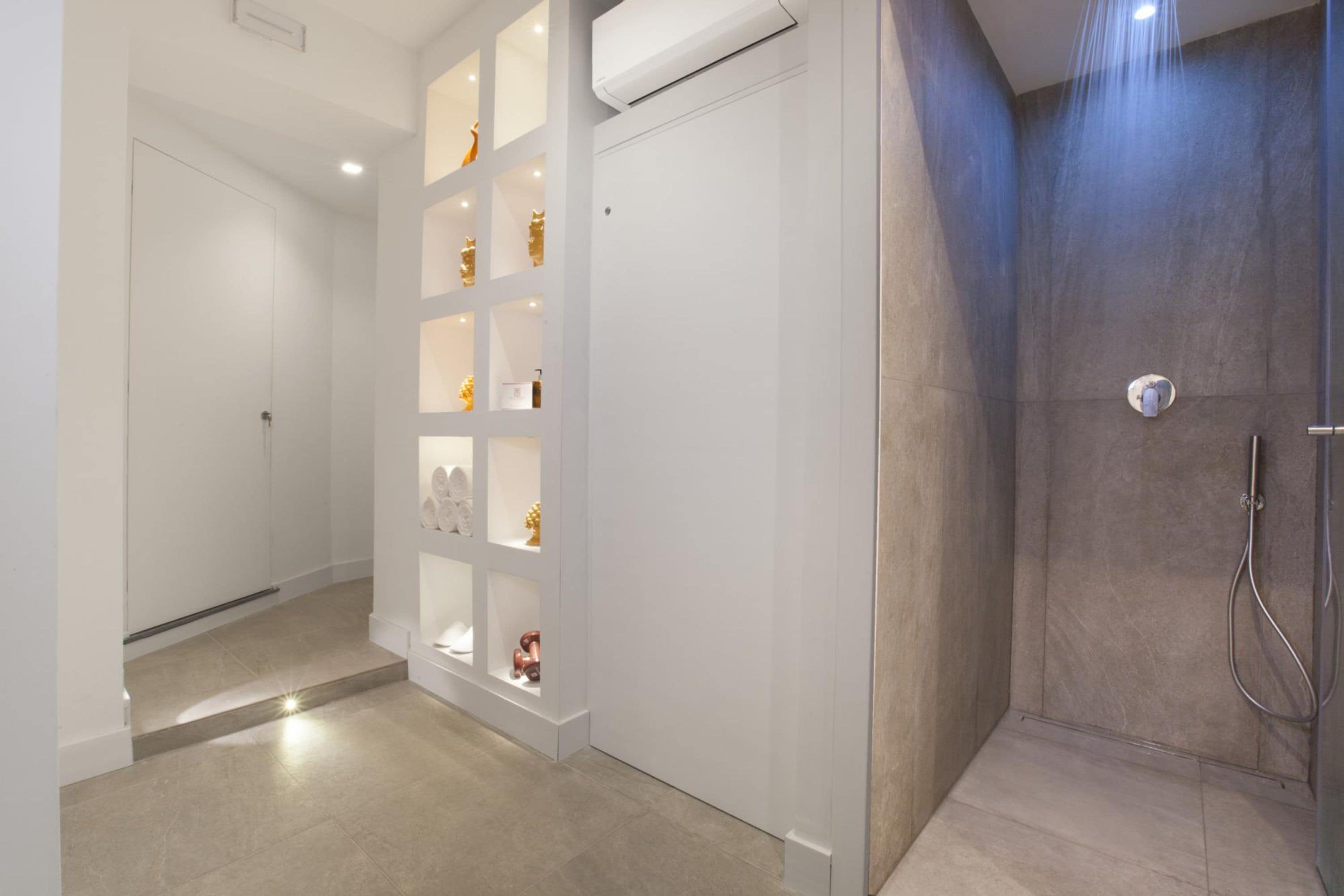 A modern bathroom with a shower, a vanity with shelves, and a toilet.