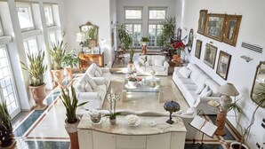 Un salón amplio con un conjunto de sofá blanco, una mesa de centro y diversas plantas en macetas.