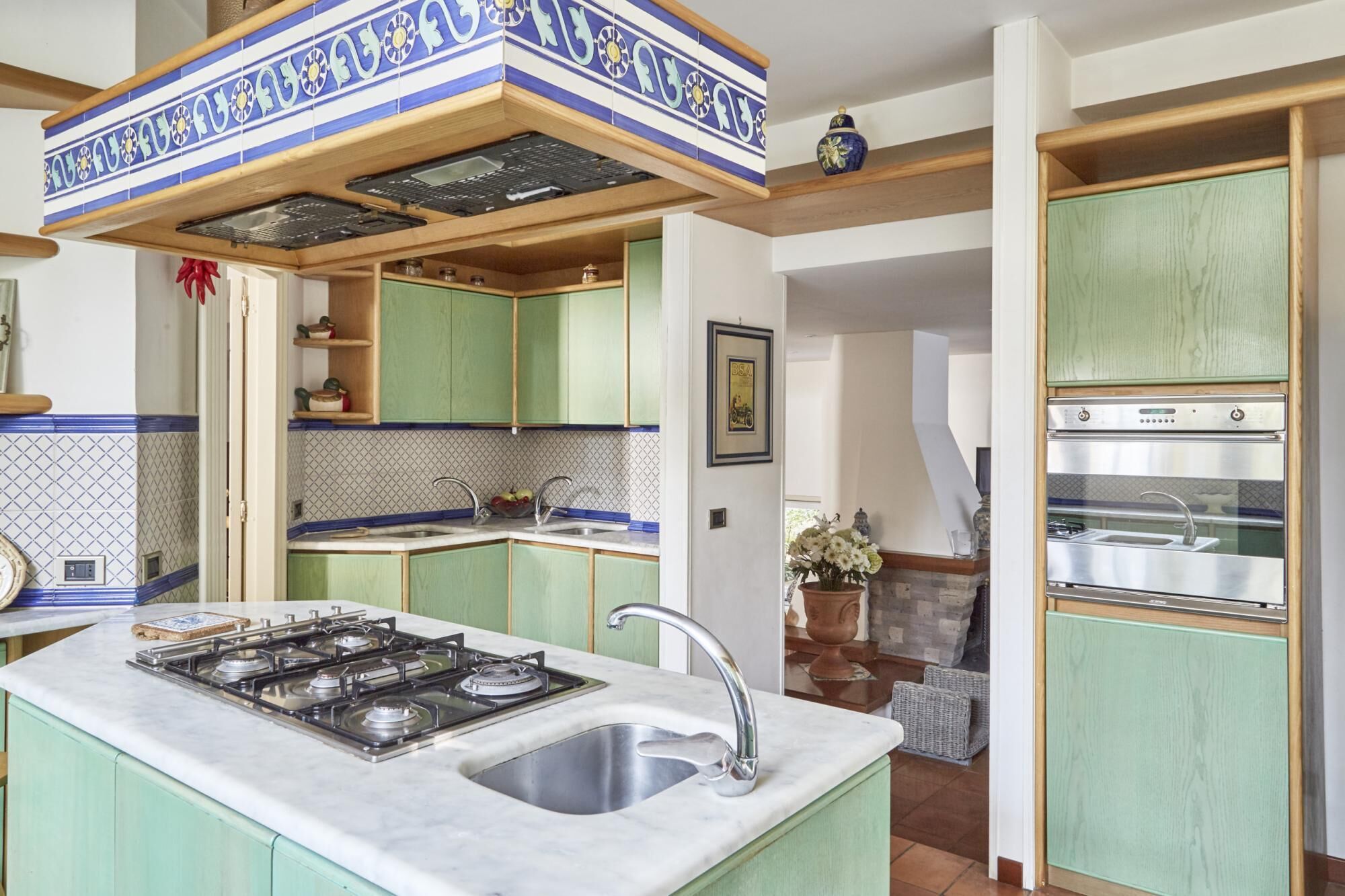 Una cocina con armarios verdes, una estufa y un lavabo.