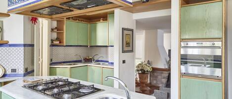 Una cocina con armarios verdes, una estufa y un lavabo.