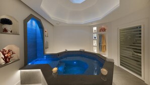 Un spa moderno con jacuzzi, tragaluz en el techo y un perchero para toallas en la pared.