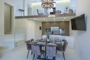 A modern kitchen with a dining area, a staircase, and a TV mounted on the wall. - Ville Il Paradiso - Villa Bacci (Greve in Chianti)