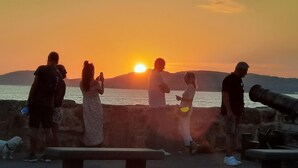 A sunset view from a stone wall with benches and a cannon. - Casa Alice 1 Bedrooms Apartment in Alghero (Alghero)