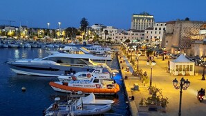 A marina with various boats docked, a small white building, and a stone wall. - Casa Alice 1 Bedrooms Apartment in Alghero (Alghero)