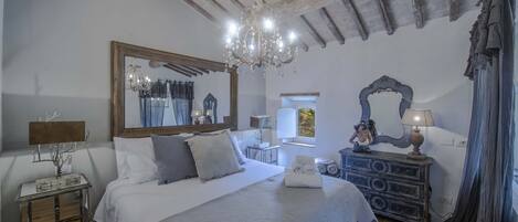 Un dormitorio con una cama grande, una araña, un aparador y un espejo.