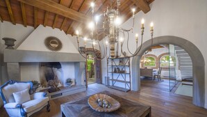 Uma sala de estar acolhedora com lareira, um candelabro e uma mesa de madeira rústica.