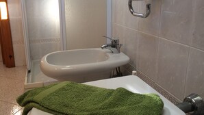 Un baño con un bidé, un lavabo y un perchero para toallas.