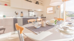 Una cucina moderna con mobili bianchi, un tavolo da pranzo per due persone e vista sull'esterno.