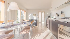 Una cucina moderna con zona pranzo, elettrodomestici in acciaio inossidabile e un'ampia finestra che offre luce naturale.