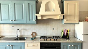 A kitchen with teal cabinets, a white backsplash, a gas stove, a dishwasher, and a sink. - Casa Ilaria 2 Bedrooms Apartment in Alghero (Alghero)