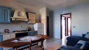 A compact living space with a kitchen, dining area, and a sofa. - Casa Ilaria 2 Bedrooms Apartment in Alghero (Alghero)
