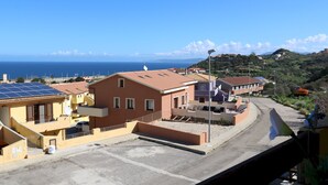 Une zone résidentielle côtière avec des maisons, un ciel dégagé et la mer en arrière-plan.