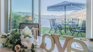 A table with a 'LOVE' decoration, a bouquet of flowers, and a view of an outdoor patio with chairs and an umbrella. - La Dolce Vista in Perledo (Perledo)