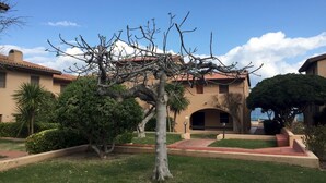 Un edificio con techo de tejas, rodeado de césped cuidado y algunos árboles.