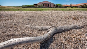 Ein Haus mit steinernem Fundament und einem großen Baum im Vordergrund.