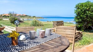 Ein Holztisch mit gemustertem Tischläufer, umgeben von einer Steinmauer und Blick auf das Meer.