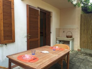 Une table en bois avec des sets de table orange, un verre transparent et une assiette blanche.