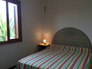 Ein Schlafzimmer mit Bett, Nachttisch, Lampe, Fenster und Wand mit Dekoration.
