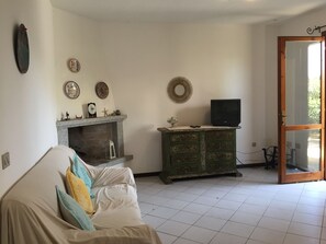 Ein Wohnzimmer mit Kamin, einem grünen Schrank, einem Fernseher und einer Couch mit Kissen.