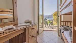 A bedroom with a wooden desk, a bed, and a balcony with a table and chairs. - Palma Romantic Dream (Perledo)